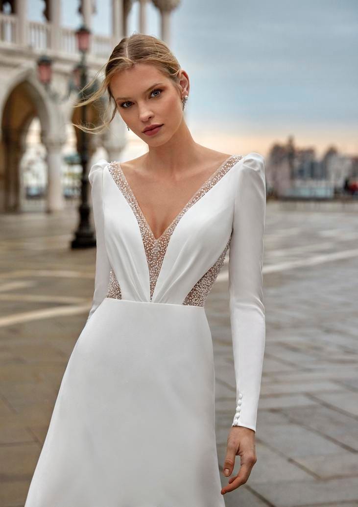 Sposa con capelli legati che indossa un abito da sposa a-line con scollo a V mentre si trova in una piazza.