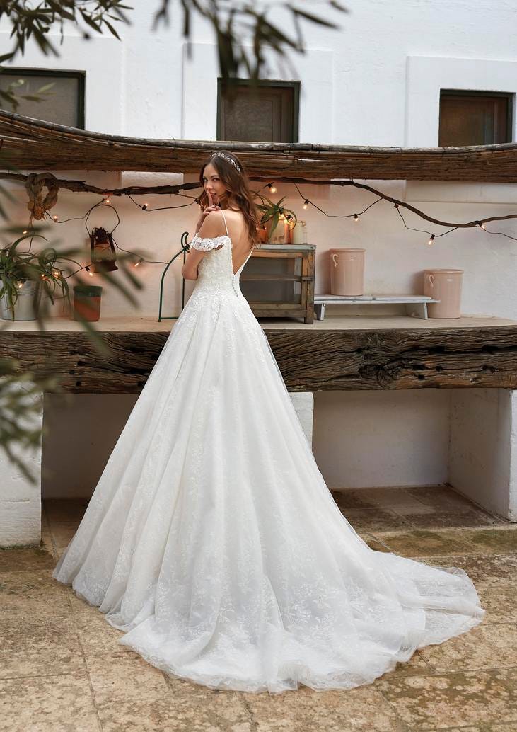 Mariée se tenant devant une table en bois sur laquelle les invités pourront se servir à manger lors du mariage.